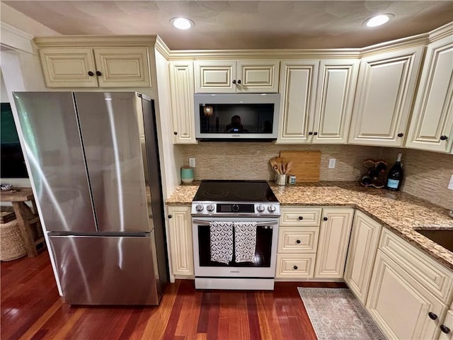 10 Lakeside Dr, Charlestown, RI 02813 - kitchen featuring appliances with stainless steel finishes, cream cabinets, dark wood finished floors, light stone counters, and decorative backsplash