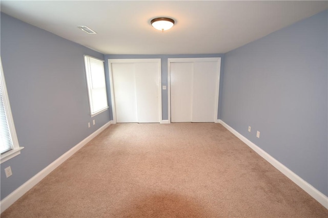 92 Trout Dr, Middletown, RI 02842 - unfurnished bedroom featuring two closets, multiple windows, and light carpet