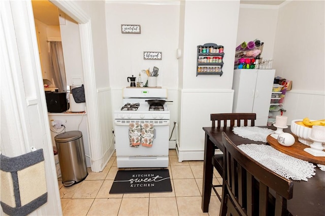 467 Plainfield St, Providence, RI 02909 - kitchen with gas range gas stove, light tile patterned floors, and wainscoting