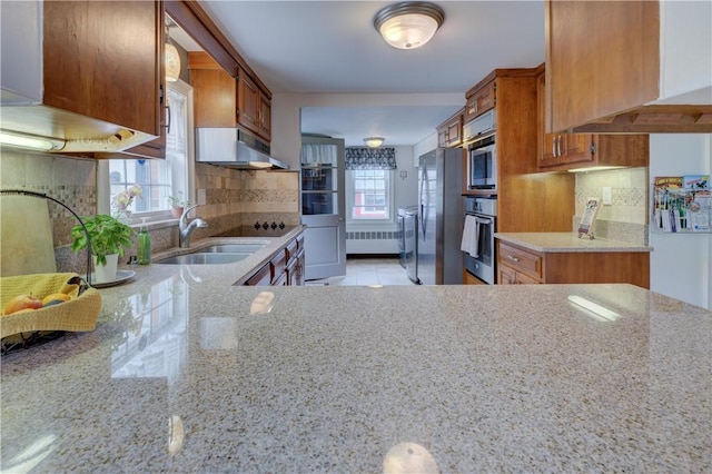 426 Buxton St, North Smithfield, RI 02896 - kitchen with under cabinet range hood, stainless steel appliances, light stone counters, and brown cabinetry