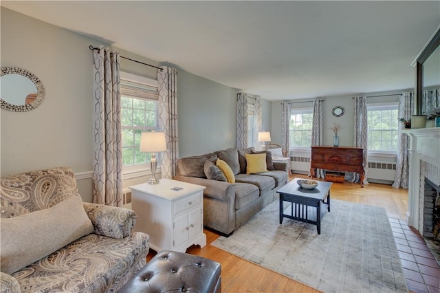 426 Buxton St, North Smithfield, RI 02896 - living room with radiator, light wood finished floors, and a fireplace with flush hearth
