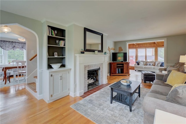 426 Buxton St, North Smithfield, RI 02896 - living area featuring light wood-style flooring, built in shelves, a fireplace with flush hearth, stairway, and arched walkways