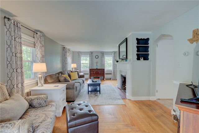 426 Buxton St, North Smithfield, RI 02896 - living room featuring a fireplace with flush hearth, arched walkways, and radiator