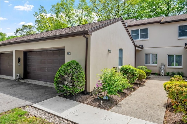 2970 Mendon Rd Unit 154, Cumberland, RI 02864 - view of side of home featuring stucco siding, an attached garage, and a shingled roof