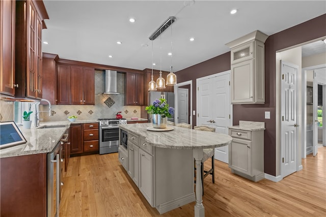 123 Castle Rocks Rd, Warwick, RI 02886 - kitchen featuring wall chimney range hood, appliances with stainless steel finishes, light wood-type flooring, a kitchen bar, and recessed lighting