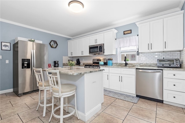 229 Roger Williams Ave, East Providence, RI 02916 - kitchen featuring appliances with stainless steel finishes, decorative backsplash, crown molding, white cabinets, and a kitchen island