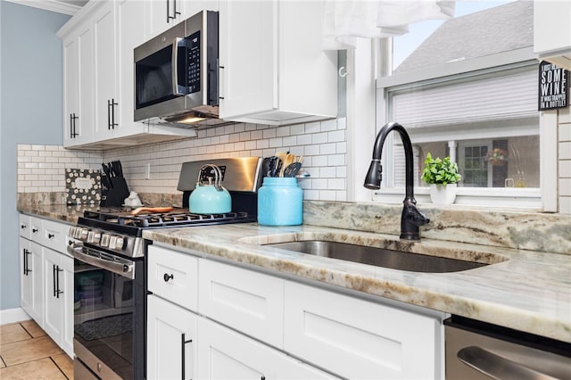229 Roger Williams Ave, East Providence, RI 02916 - kitchen featuring stainless steel appliances, light stone counters, white cabinetry, tasteful backsplash, and light tile patterned floors