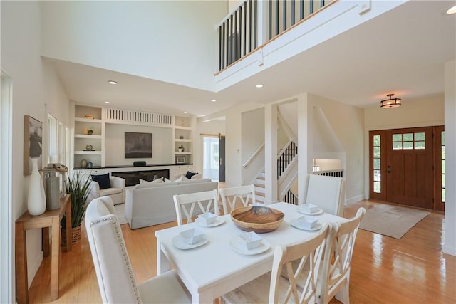 26 Old Stone Church Rd, Little Compton, RI 02837 - dining area featuring a towering ceiling, light wood-style flooring, stairs, built in features, and recessed lighting