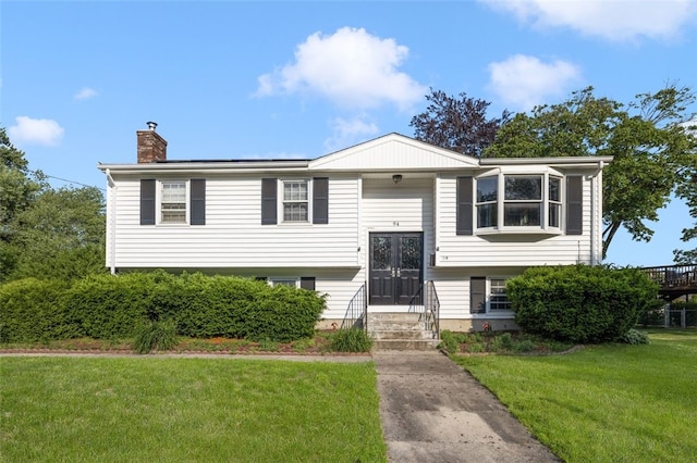 94 Waterman Ave, Warwick, RI 02889 - raised ranch featuring french doors, a chimney, a front yard, and entry steps