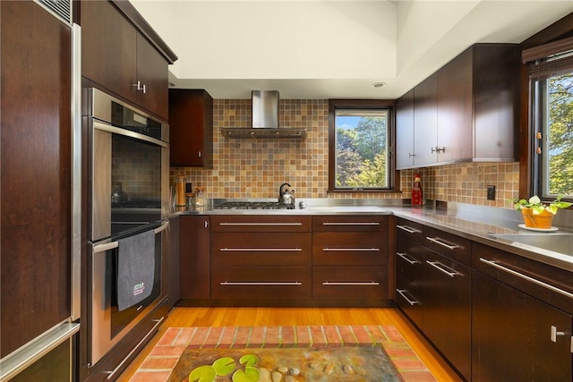 11 Mill Brook Ct, Charlestown, RI 02813 - kitchen featuring stainless steel countertops, wall chimney range hood, appliances with stainless steel finishes, light wood finished floors, and tasteful backsplash