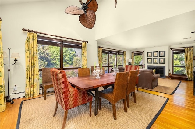 11 Mill Brook Ct, Charlestown, RI 02813 - dining room with a ceiling fan, light wood-style floors, a high ceiling, and a glass covered fireplace