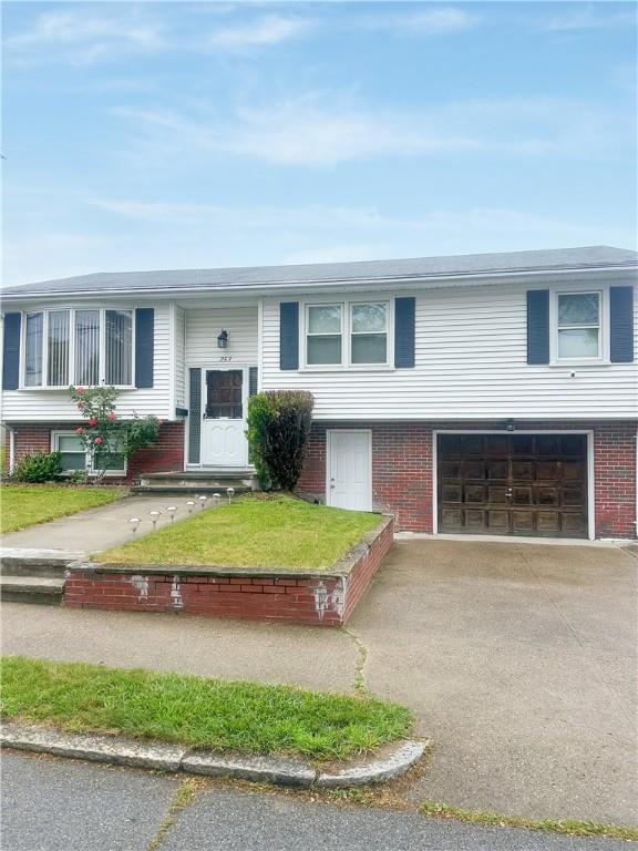 253 Nelson St, Providence, RI 02908 - bi-level home featuring an attached garage, asphalt driveway, and brick siding