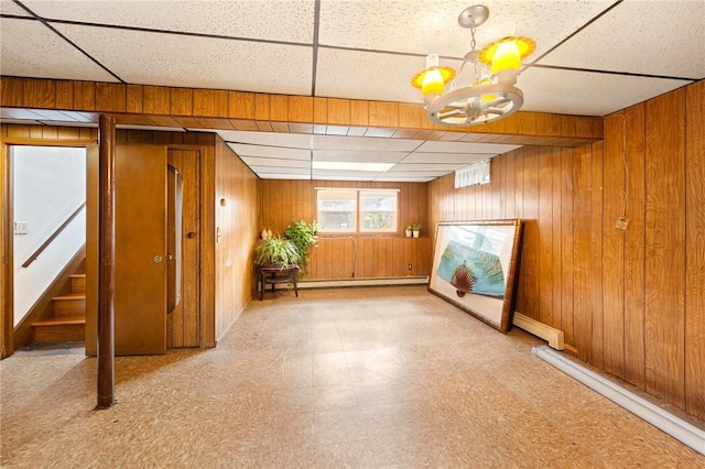 253 Nelson St, Providence, RI 02908 - below grade area with a drop ceiling, baseboard heating, wooden walls, tile patterned floors, and a chandelier