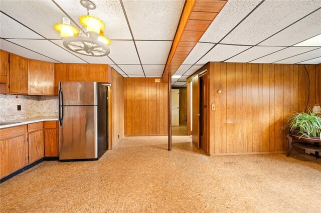 253 Nelson St, Providence, RI 02908 - kitchen with freestanding refrigerator, brown cabinets, a drop ceiling, wood walls, and light countertops