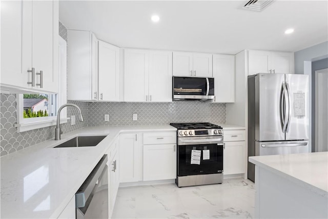 57 Wilson Ave, Johnston, RI 02919 - kitchen with appliances with stainless steel finishes, white cabinetry, recessed lighting, tasteful backsplash, and light marble finish floors