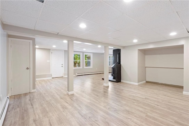 57 Wilson Ave, Johnston, RI 02919 - basement with baseboard heating, a wood stove, light wood-style flooring, and a drop ceiling