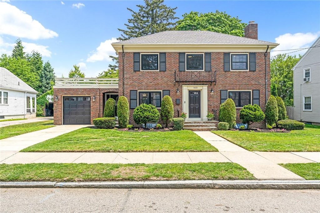 103 Jastram St, Providence, RI 02908 - colonial inspired home with an attached garage, brick siding, a chimney, a front yard, and concrete driveway