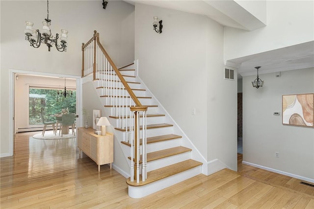 9 Beacon Hill Dr, Warwick, RI 02886 - staircase featuring a chandelier, wood-type flooring, a towering ceiling, and a baseboard radiator