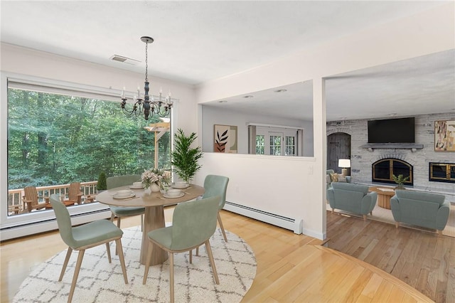 9 Beacon Hill Dr, Warwick, RI 02886 - dining area featuring a stone fireplace, a baseboard radiator, wood finished floors, and a chandelier