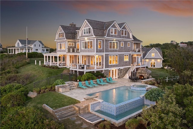 1210 Graces Cove Rd, Block Island, RI 02807 - back of property at dusk featuring a balcony, an in-ground hot tub, stairs, a fenced backyard, and a patio