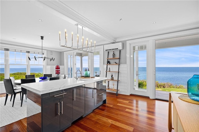 1210 Graces Cove Rd, Block Island, RI 02807 - kitchen with an AC wall unit, a chandelier, crown molding, dark wood-type flooring, and an island with sink