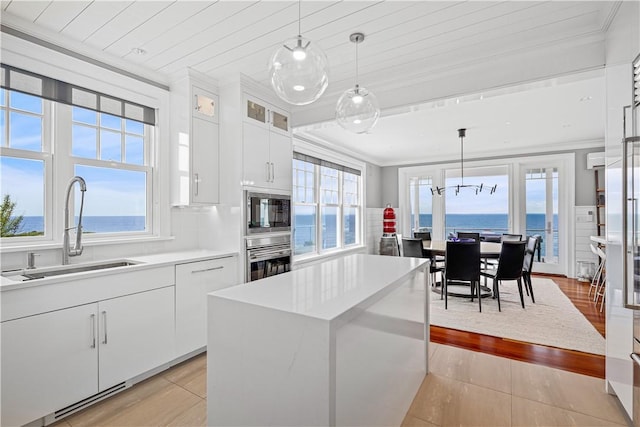 1210 Graces Cove Rd, Block Island, RI 02807 - kitchen with black microwave, oven, ornamental molding, light countertops, and white cabinets