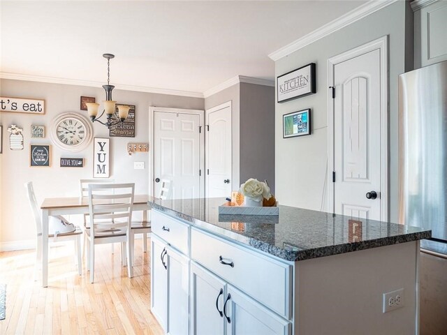 19 Revere Ave, West Warwick, RI 02893 - kitchen featuring a chandelier, light wood-style flooring, crown molding, dark stone countertops, and a kitchen island