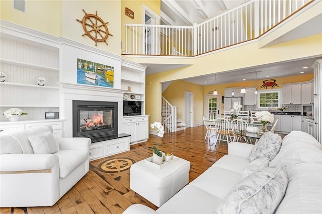 37 Teal Rd, South Kingstown, RI 02879 - living area with light wood finished floors, stairway, a glass covered fireplace, a towering ceiling, and built in features