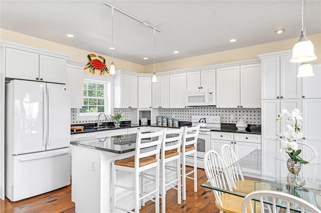 37 Teal Rd, South Kingstown, RI 02879 - kitchen with white appliances, rail lighting, dark countertops, hardwood / wood-style flooring, and white cabinetry