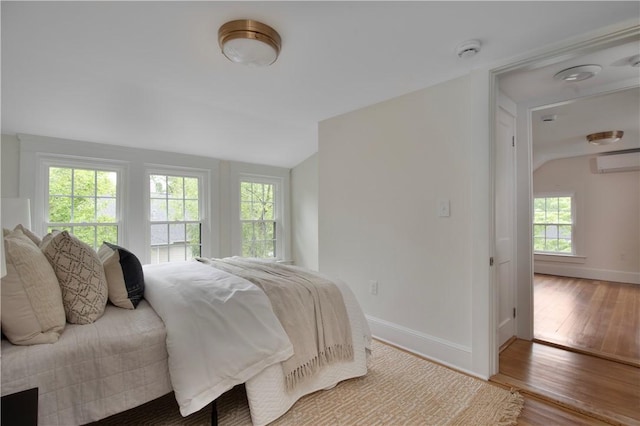 175 Freeman Pkwy, Providence, RI 02906 - bedroom with vaulted ceiling, a wall mounted AC, wood finished floors, and multiple windows