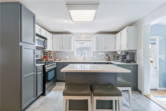 75 Crescent Ave, Cranston, RI 02910 - kitchen featuring appliances with stainless steel finishes, gray cabinetry, backsplash, a breakfast bar area, and light countertops