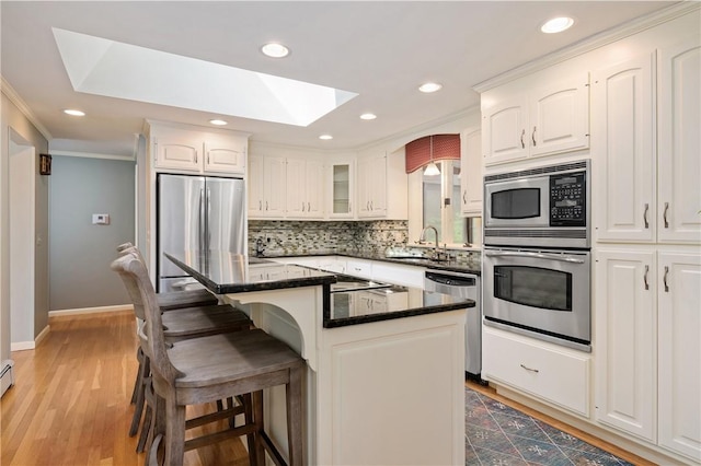 70 High Ridge Dr, Cumberland, RI 02864 - kitchen with appliances with stainless steel finishes, a skylight, a kitchen breakfast bar, decorative backsplash, and ornamental molding