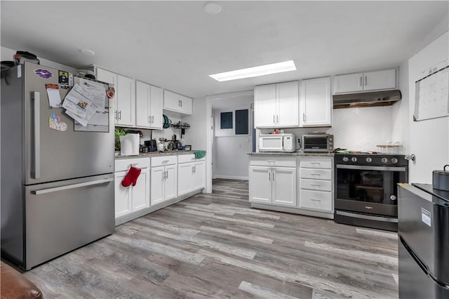 101 Benefit St, Pawtucket, RI 02860 - kitchen with stainless steel appliances, under cabinet range hood, white cabinets, and light wood-style floors