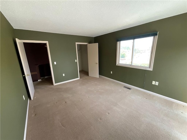 511 Child St Unit 101, Warren, RI 02885 - unfurnished bedroom featuring a walk in closet, light colored carpet, a closet, and a textured ceiling