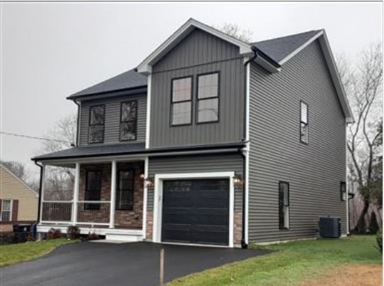 104 Crescent Rd, Pawtucket, RI 02861 - view of front of property featuring an attached garage, board and batten siding, covered porch, asphalt driveway, and a front yard