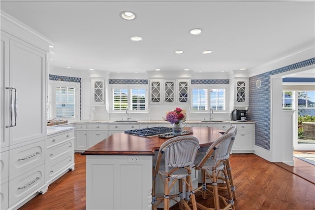 9 Arraquat Rd, Westerly, RI 02891 - kitchen with stainless steel gas stovetop, wallpapered walls, a center island, a breakfast bar, and wood finished floors