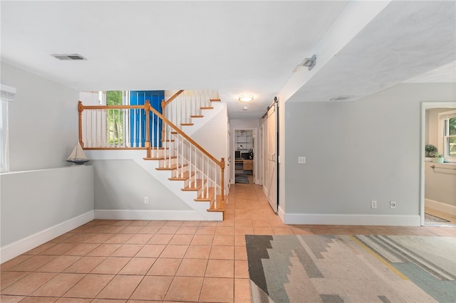 11 Burr Ave, Barrington, RI 02806 - foyer with light tile patterned floors, stairs, a barn door, and healthy amount of natural light