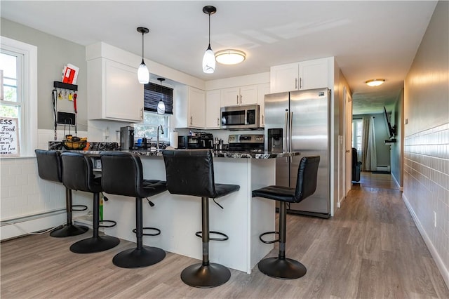 111 Belgium St, Cranston, RI 02920 - kitchen featuring stainless steel appliances, dark countertops, a peninsula, a breakfast bar, and wood finished floors