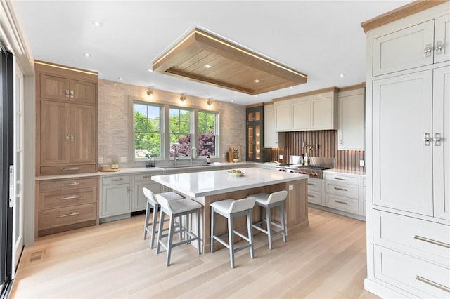 35 Coggeshall Ave, Newport, RI 02840 - kitchen featuring a kitchen bar, light wood finished floors, backsplash, light countertops, and a tray ceiling