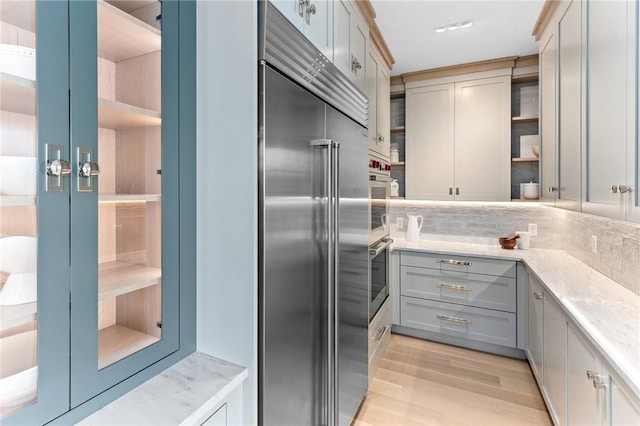 35 Coggeshall Ave, Newport, RI 02840 - kitchen featuring high end fridge, open shelves, tasteful backsplash, light wood-type flooring, and light stone counters