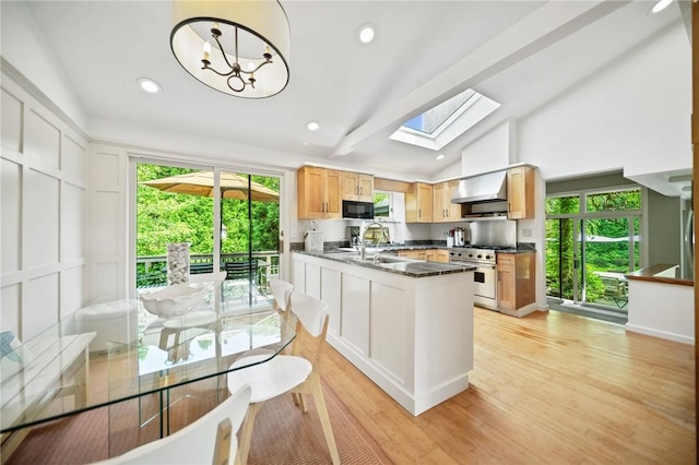 20 Wagner Rd, Westerly, RI 02891 - kitchen with high end stainless steel range oven, wall chimney exhaust hood, a skylight, dark countertops, and light wood finished floors