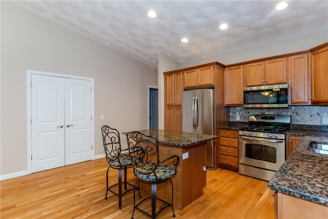 1285 Hartford Ave Unit 25, Johnston, RI 02919 - kitchen with stainless steel appliances, a breakfast bar, brown cabinets, tasteful backsplash, and vaulted ceiling