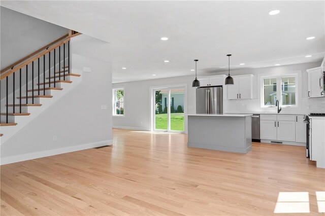 52 Governor St, Cumberland, RI 02864 - kitchen with appliances with stainless steel finishes, a center island, recessed lighting, light wood-type flooring, and backsplash
