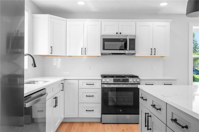 52 Governor St, Cumberland, RI 02864 - kitchen featuring stainless steel appliances, recessed lighting, light wood-style floors, tasteful backsplash, and white cabinetry