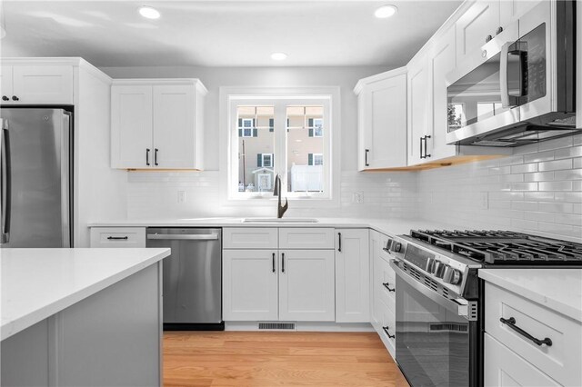 52 Governor St, Cumberland, RI 02864 - kitchen with appliances with stainless steel finishes, light countertops, recessed lighting, white cabinetry, and light wood finished floors