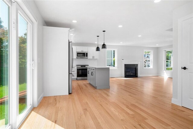 52 Governor St, Cumberland, RI 02864 - kitchen with stainless steel appliances, light wood-style floors, open floor plan, a glass covered fireplace, and light countertops