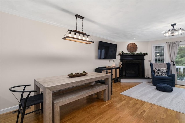88 Red Brook Ln Unit 88, West Warwick, RI 02893 - dining area with a fireplace with raised hearth, light wood finished floors, ornamental molding, and a chandelier