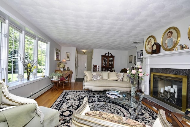 1 Butts Rock Rd, Little Compton, RI 02837 - living room with wood finished floors, a baseboard radiator, a fireplace, and a textured ceiling