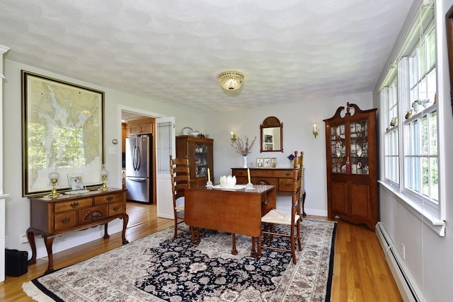 1 Butts Rock Rd, Little Compton, RI 02837 - office area featuring a baseboard heating unit, light wood-style floors, and a textured ceiling