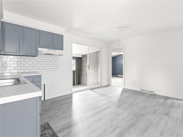 25 Martha Rd, East Providence, RI 02916 - kitchen with under cabinet range hood, light wood finished floors, light countertops, and decorative backsplash